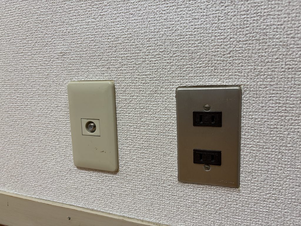 黄ばんだテレビアンテナ端子プレートと、くすんだ金属製コンセントプレート